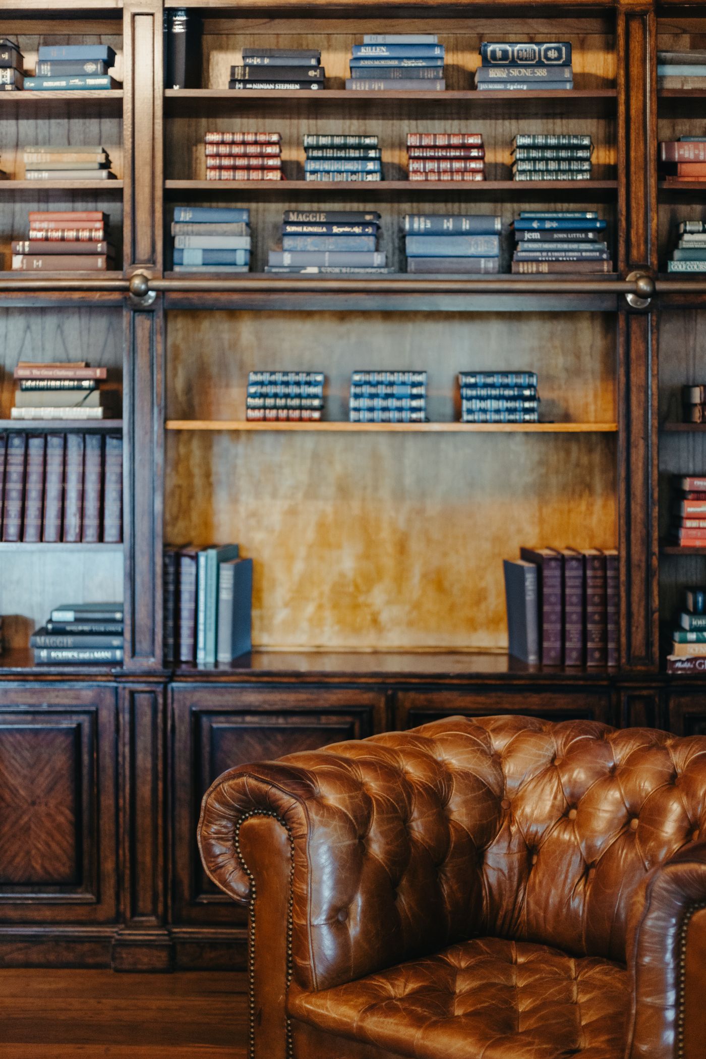 A private wood-panelled library with worn leather chairs and full shelves